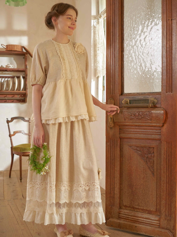 Wearing a soft beige vintage outfit with lace and ruffles, a woman stands by a carved wooden door in a romantic cottagecore setting.