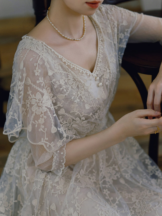 Close-up of a vintage-style lace dress with floral embroidery and pearl neckline, highlighting the soft fairycore charm and delicate textures.