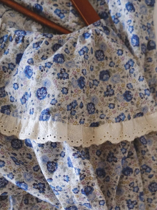 Close-up of a blue floral fabric with delicate eyelet lace trim, highlighting the romantic cottagecore details of a fairytale-inspired loungewear dress.