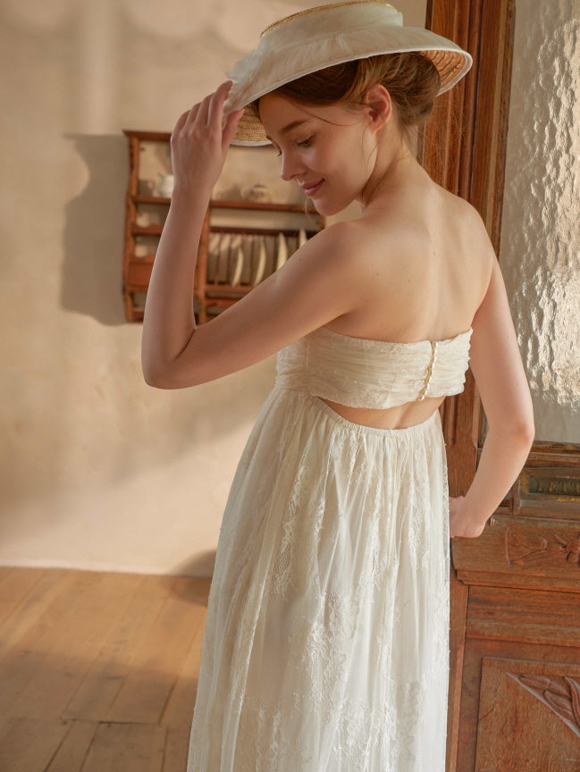 A dreamy fairycore moment as the model lifts the hem of her ivory lace dress, glowing in soft light with delicate embroidered textures.