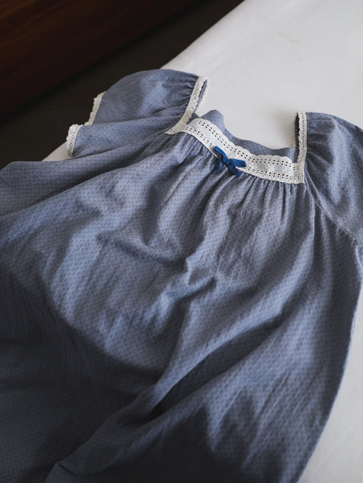 A lavender nightgown with lace-trimmed square neckline and puff sleeves lies softly on a bed, capturing a fairytale-inspired cottagecore feeling.