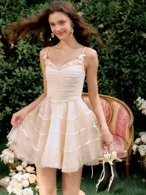 A young woman smiles warmly in a tiered ivory tulle dress, holding her shoes beside a vintage sofa, radiating soft princess coquette elegance.