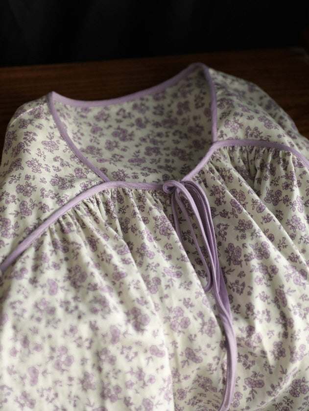 Close-up of a soft cream and lavender floral pajama top with ribbon tie neckline, highlighting vintage cottagecore loungewear details.