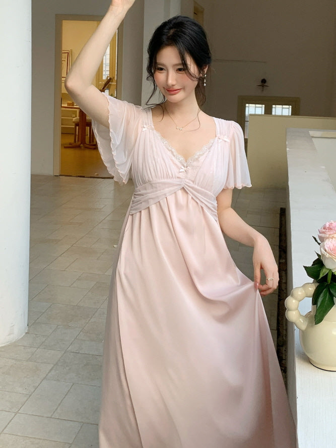 Model wears a princesscore-style pale pink loungewear dress with delicate pleated sleeves and ribbon details, radiating romantic cottagecore charm.