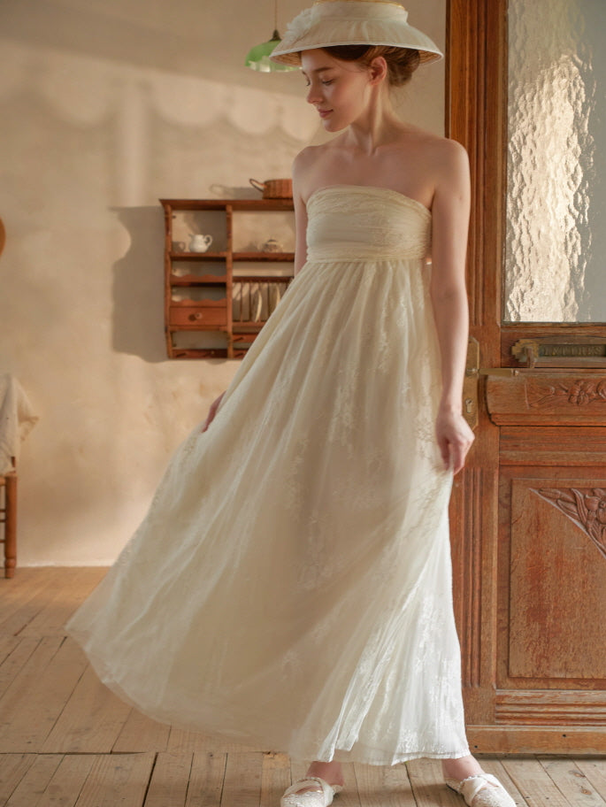 A model gracefully holds the skirt of her fairytale-inspired ivory lace gown, evoking a dreamy, romantic atmosphere in soft lighting.