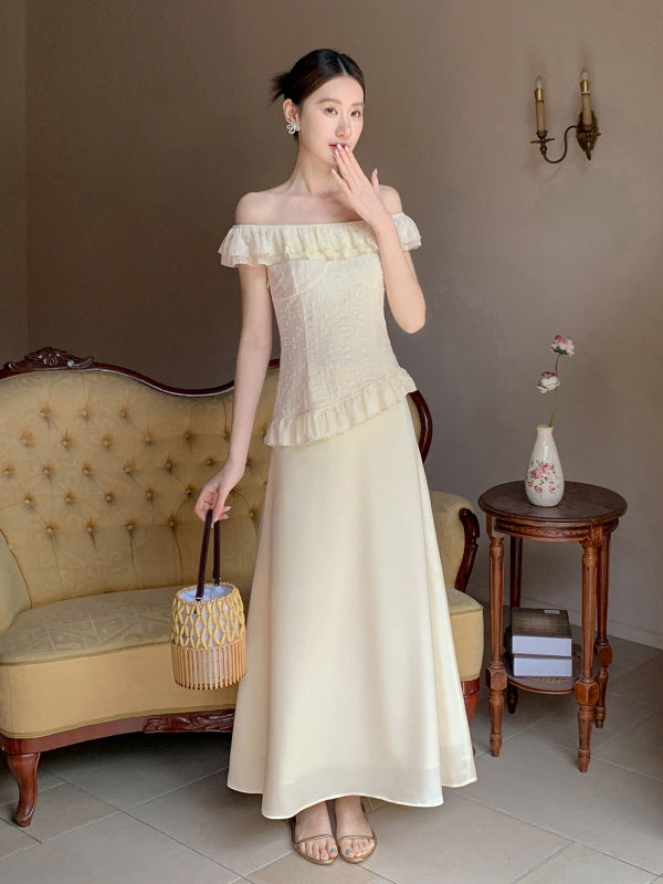 A woman wears an ivory off-shoulder ruffled top with a flowing satin skirt, styled in a vintage cottagecore room with classic furniture.