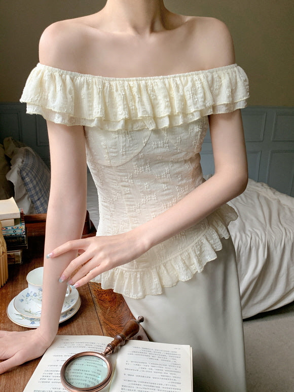 Close-up of a fairycore-inspired ivory ruffle blouse with textured fabric, paired with a soft cream skirt, styled in a dreamy, bookish setting.
