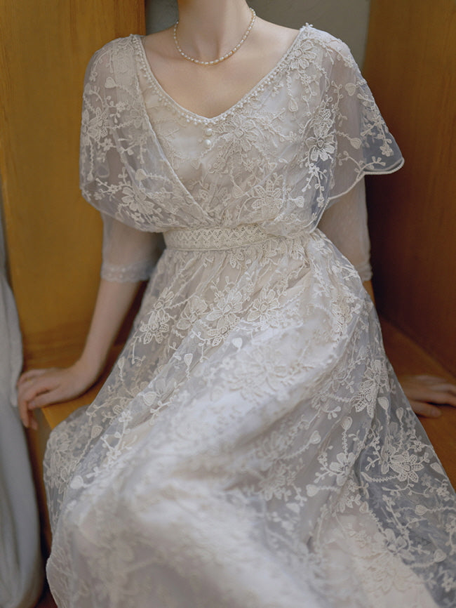A close view of a vintage-inspired lace gown featuring floral embroidery and a pearl necklace, exuding romantic and fairycore elegance.