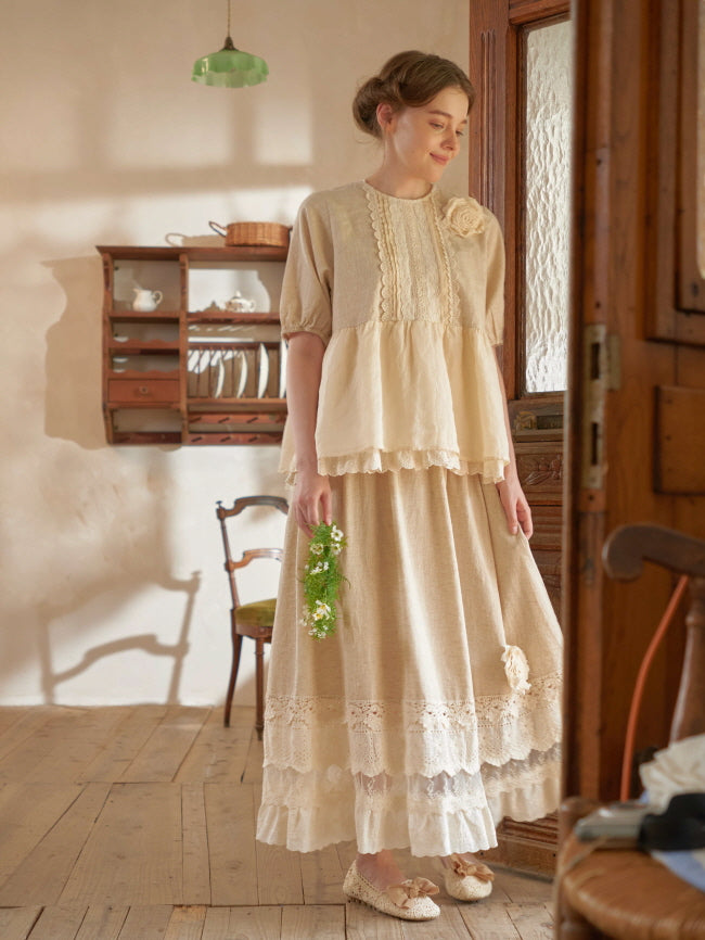 Wearing a romantic cottagecore outfit, the woman gazes down with a floral wreath in hand, framed by warm light and vintage décor.