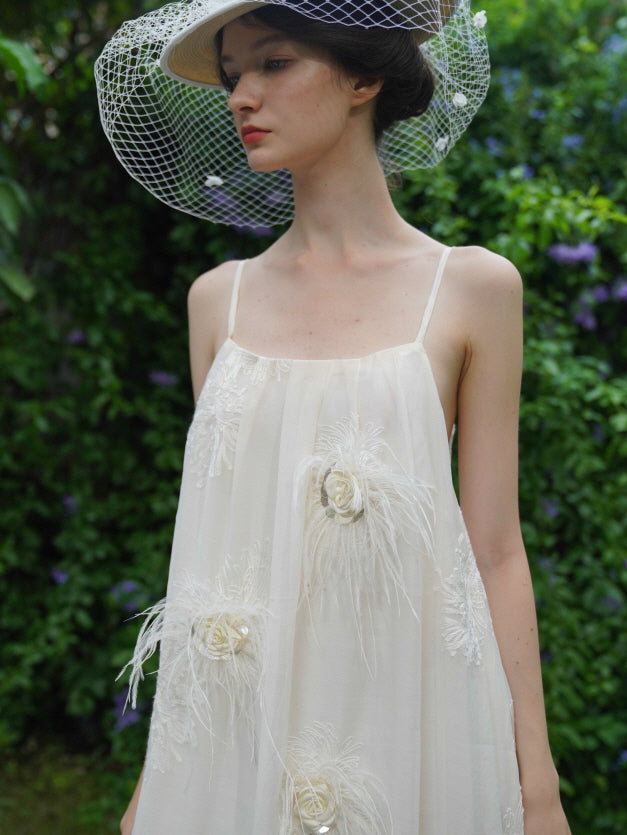 Close-up of a model in a cream fairycore dress with feather floral details and a vintage hat, styled for a soft romantic garden atmosphere.
