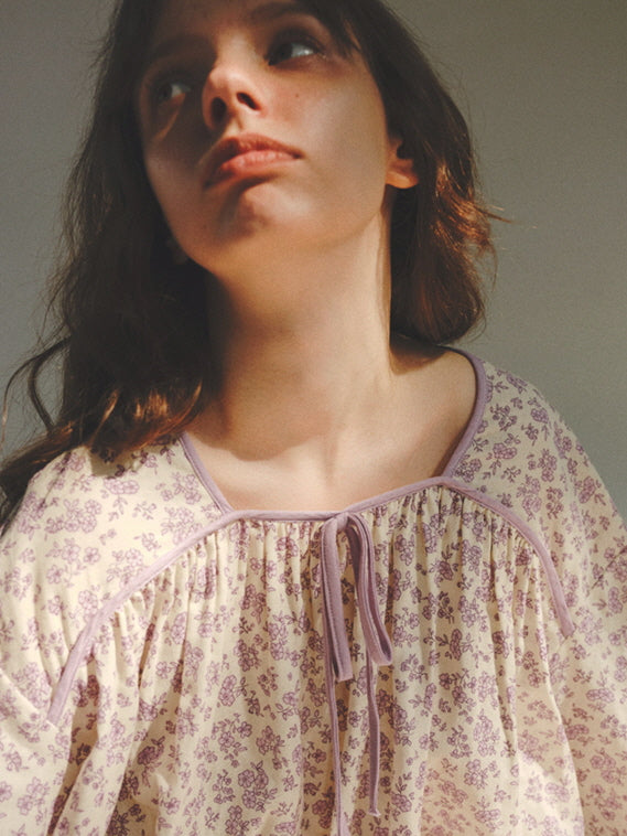 Close-up of the model in a lavender floral pajama top with ribbon tie, bathed in soft light for a romantic vintage loungewear mood.