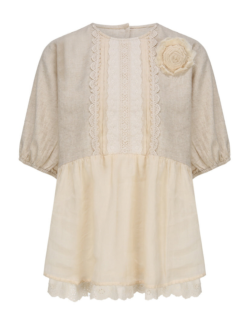 Flat-lay of a beige puff sleeve blouse with lace panel details and a fabric flower on the shoulder, perfect for a cottagecore outfit.