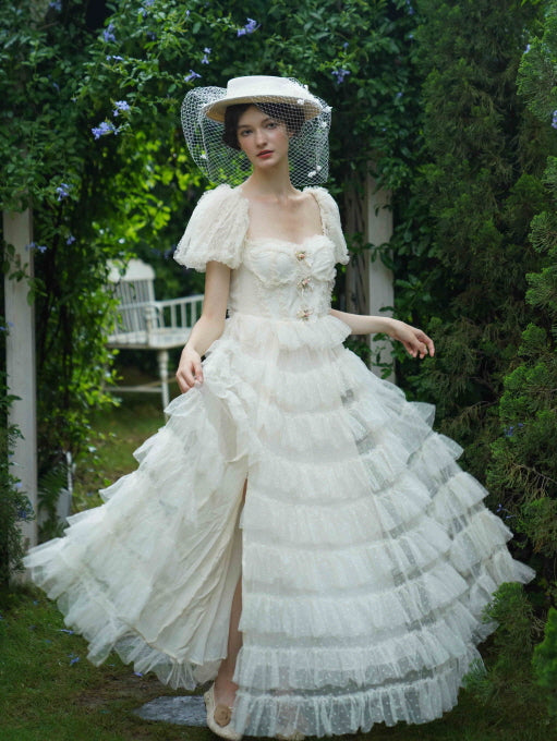 Walking through a floral garden, the model twirls in an ivory layered gown with a veiled hat, radiating soft princesscore and cottagecore elegance.