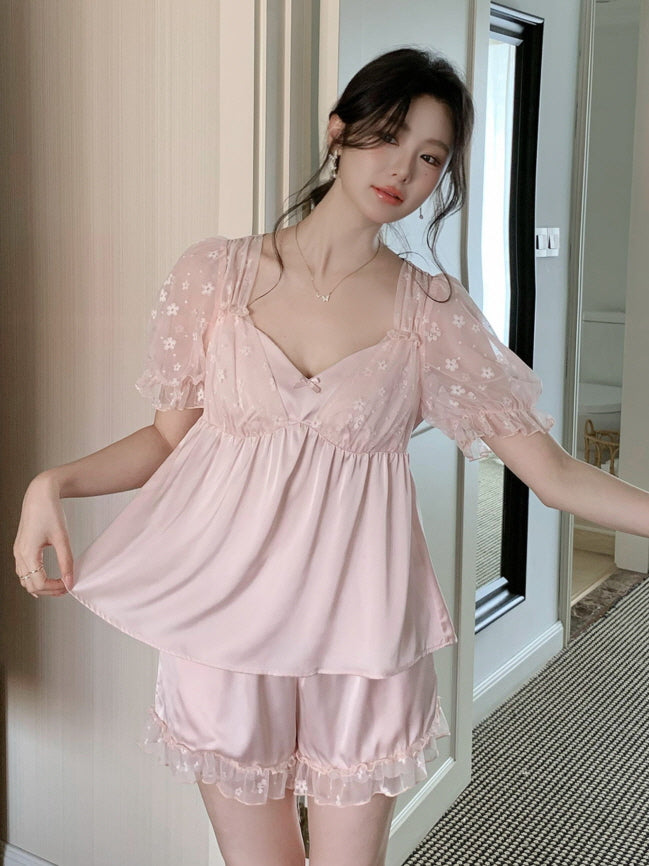 Model in a blush pink fairycore loungewear set with layered top and floral mesh puff sleeves, standing in a chic modern hallway setting.