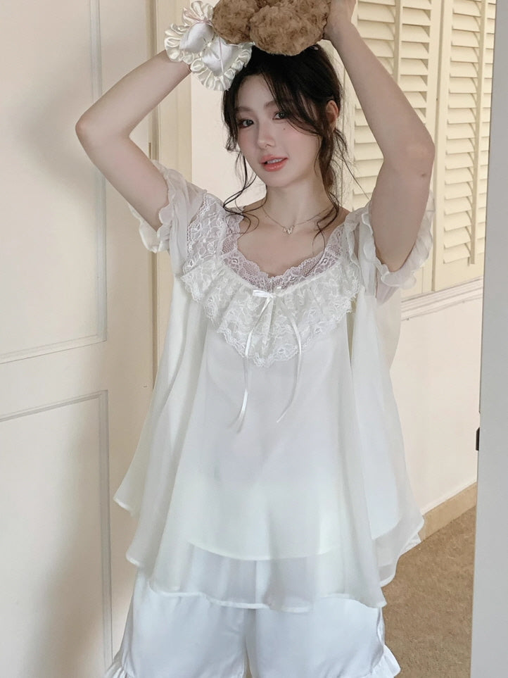 Model lifting a teddy bear above her head while wearing a flowy fairycore pajama set with sheer sleeves and romantic ribbon accents.