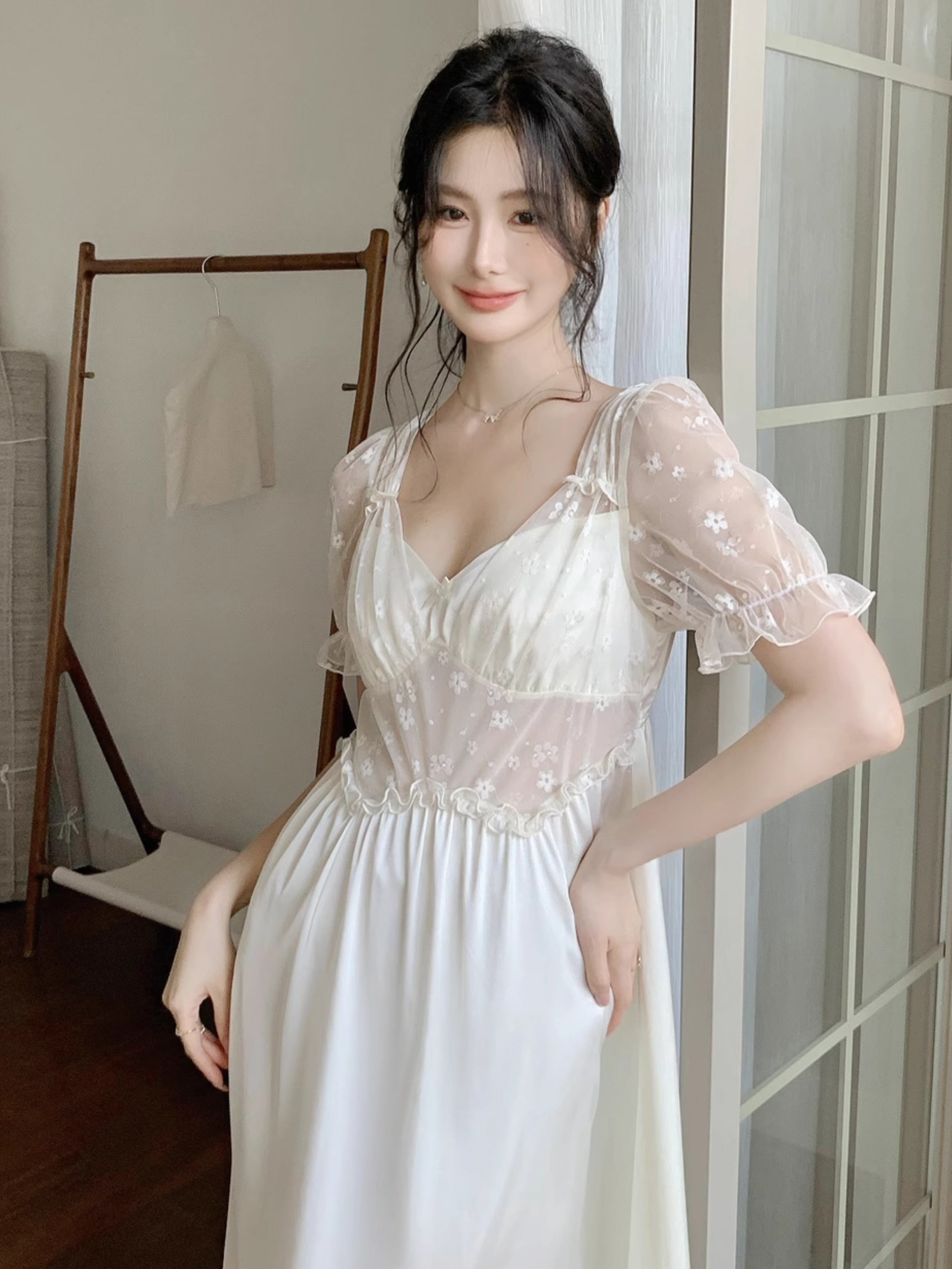 Model posing by the window in an ivory long nightgown with sheer embroidered puff sleeves and a soft gathered waist for a romantic fairycore vibe.