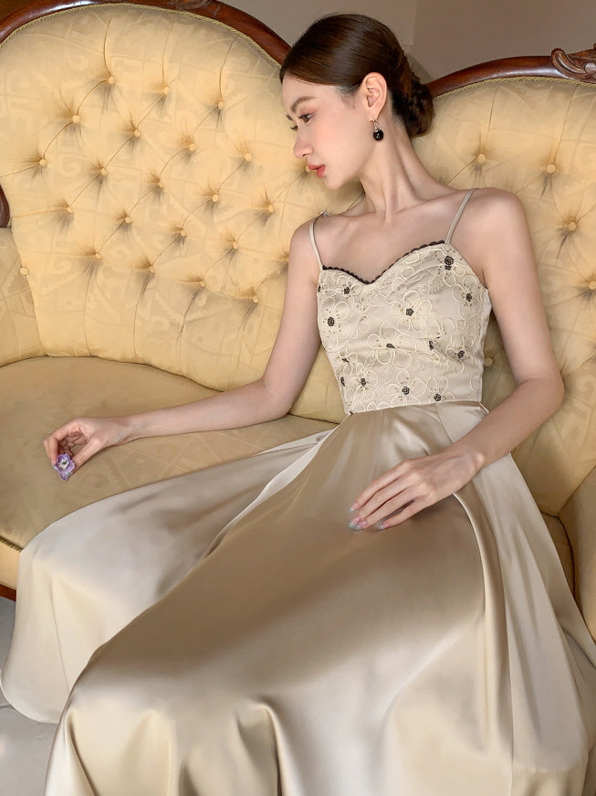 Reclining on a tufted antique sofa, a woman wears a delicate embroidered summer dress with a satin skirt, evoking a luxurious fairytale-inspired mood.