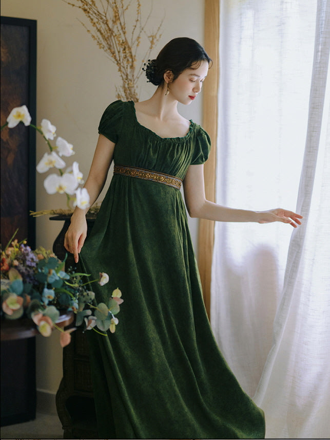 Bathed in soft natural light, the woman wears a princesscore dark green gown with gathered neckline, gently touching the curtain in a quiet scene.