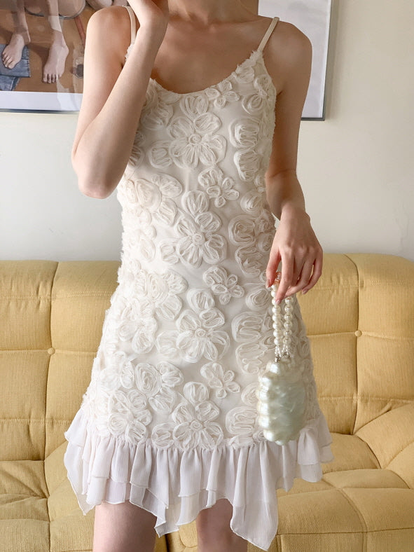 Close-up of a romantic elegant mini dress with three-dimensional flower appliqué and ruffled chiffon trim, styled with an elegant pearl accessory.