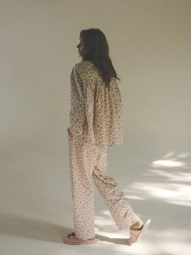 The model walks slowly through soft morning light, wearing a lavender floral pajama set that flows gently with a relaxed vintage silhouette.