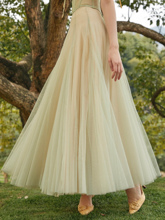 Flowing tulle skirt sways gently as the model walks through the grass in a romantic fairycore gown with soft pastel layers.