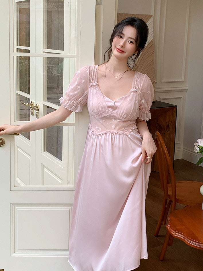 Woman smiling in a pastel pink satin nightgown with puff sleeves and floral lace bodice, styled in a romantic princesscore setting.