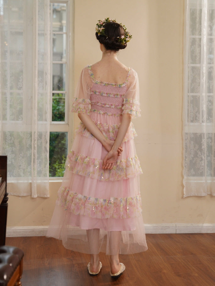 Back view of a woman in a layered pink princesscore dress with floral crown, her hands folded behind her in a romantic vintage interior.