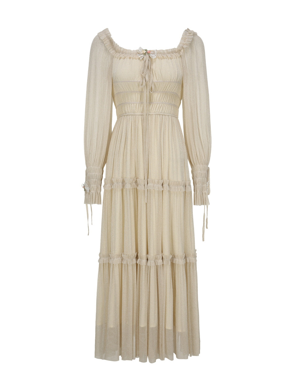 Flat-lay of a cream long-sleeve dress with shirred bodice, ribbon bow detail, and tiered ruffle skirt in a soft vintage fairytale style.