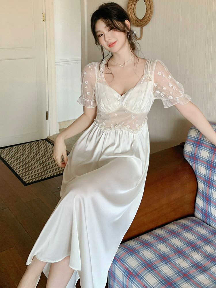 Model sitting on a wooden bench in an ivory satin nightgown with sheer puff sleeves and floral embroidery, radiating soft coquette elegance.