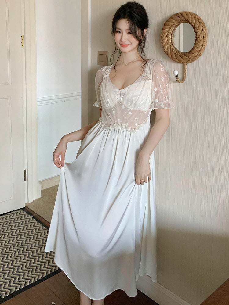 Model holding the skirt of a flowy ivory nightgown with embroidered mesh bodice and puff sleeves, styled with a dreamy fairytale look.