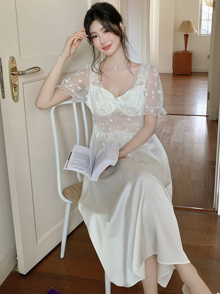 Woman reading a book in a vintage-inspired princesscore nightgown, featuring sheer floral sleeves and a satin A-line silhouette.