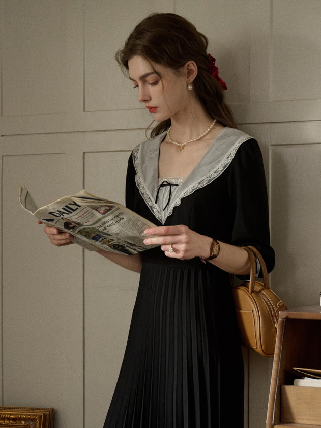 A woman wearing a romantic retro black dress with a lace-trimmed collar, styled for a casual and aesthetic reading moment with fairytale charm.