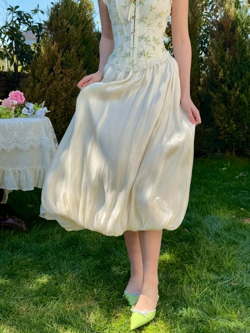 Cream balloon midi skirt with subtle sheen, paired with floral corset top and green pointed heels – soft fairytale garden outfit for women