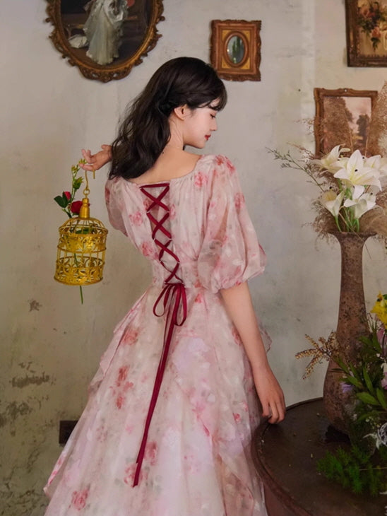 Back view of a romantic floral gown with a lace-up ribbon detail in deep red, paired with puff sleeves and a soft, ethereal cottagecore look.