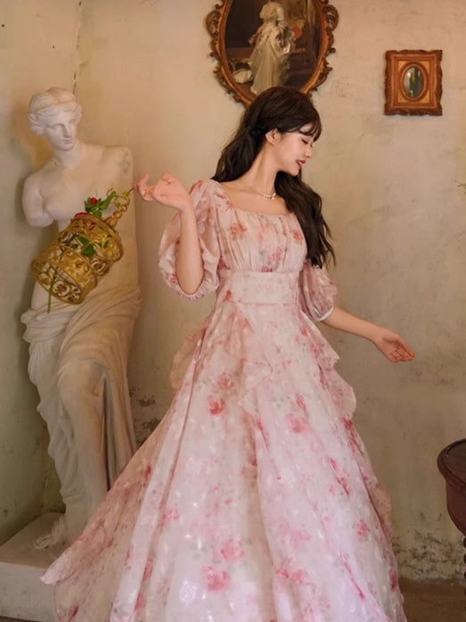 A romantic pink floral dress with layered ruffles and puff sleeves, styled with a delicate birdcage and evoking a dreamy fairytale ambiance.