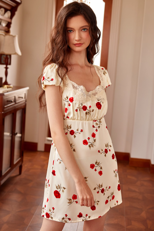 Wearing a cream night dress with red rose prints and puff sleeves, the model gives a gentle smile, blending vintage elegance with fairytale charm.