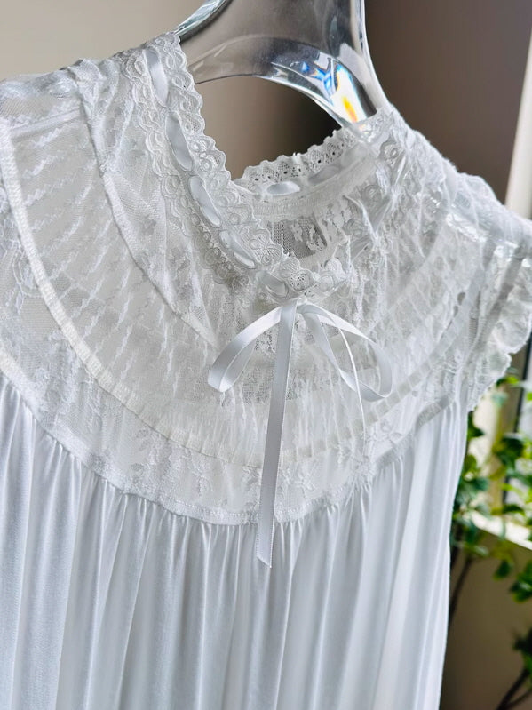 Close-up of a white vintage-style nightgown with lace yoke, pintuck detail, and satin ribbon bow, capturing delicate fairycore elegance.