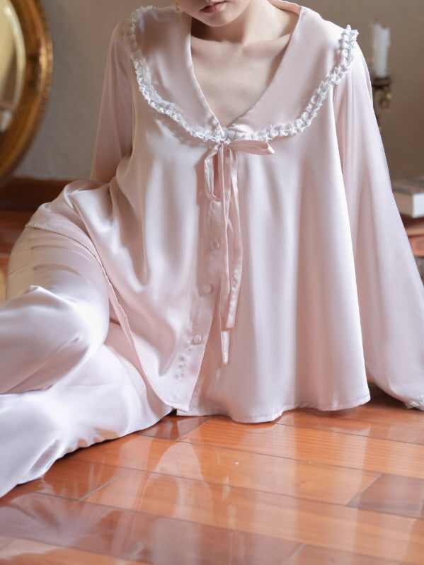 Close-up of blush pink lace-trim collar loungewear top with ribbon bow tie and button-front detail, romantic vintage coquette sleepwear.