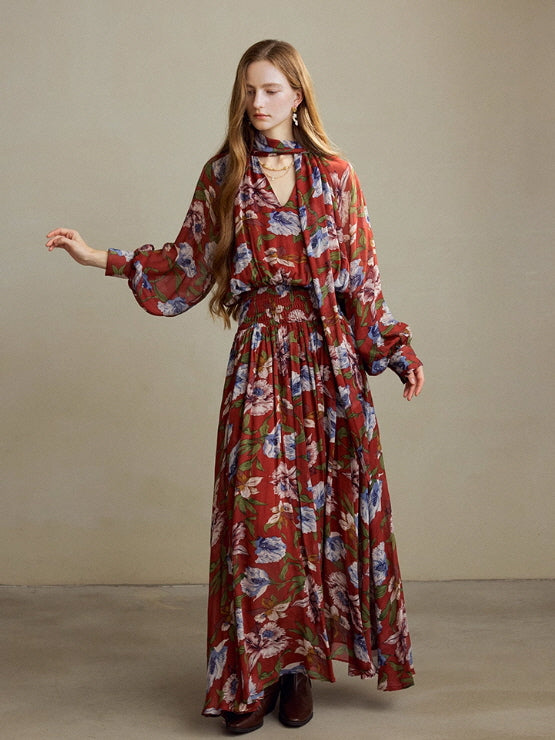 Model wearing a flowing red floral maxi dress with a long scarf detail, standing in a soft neutral studio background for a vintage cottagecore aesthetic.