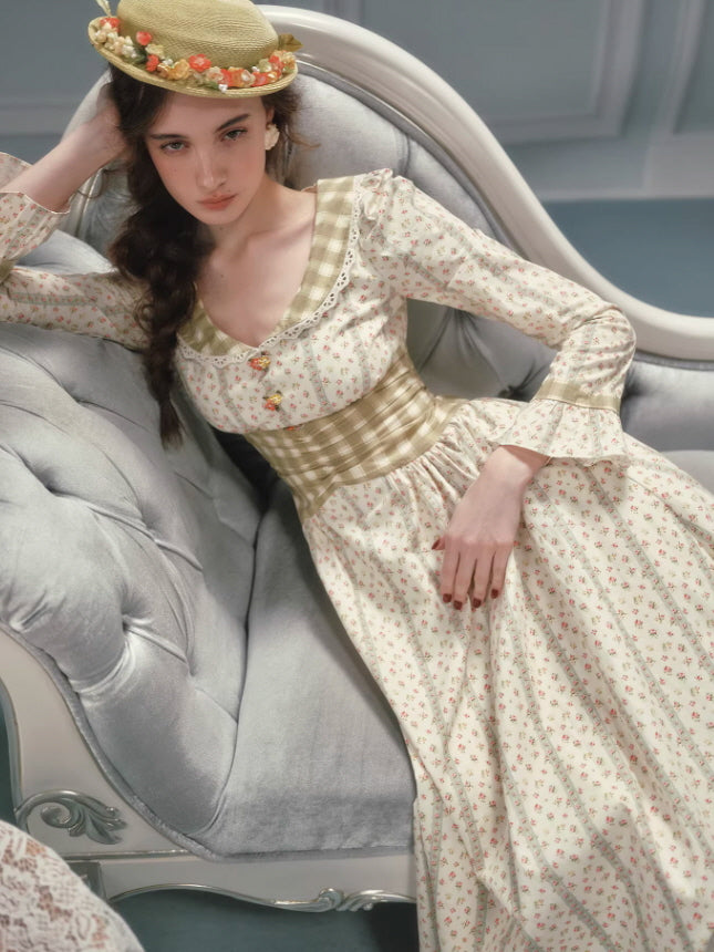 Vintage cottagecore floral dress worn by a model reclining on a classic sofa, showcasing a gathered corset waist, delicate lace details, soft floral pattern, and a timeless romantic fairytale aesthetic.