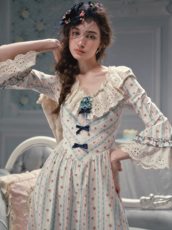Romantic vintage floral dress featuring a lace-trimmed ruffled neckline, blue ribbon corset detail, and delicate floral stripes, styled in a soft cottagecore fairytale aesthetic.