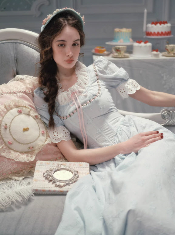 Vintage-inspired pale blue dress featuring delicate lace embroidery, ribbon neckline detail, and a flowing skirt, creating a calm fairycore and cottagecore aesthetic mood.