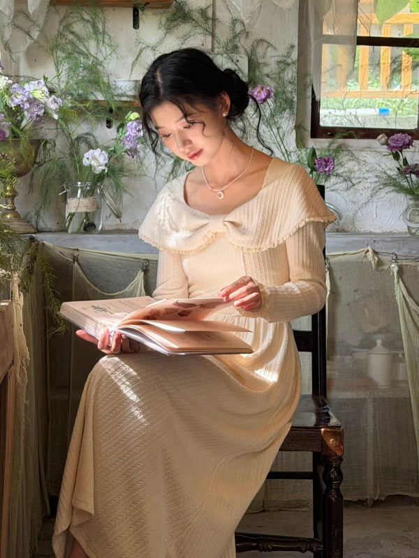 A woman wearing an ivory knit dress with a sailor collar, styled while reading a book in a vintage cottage interior, creating a calm fairycore and cottagecore aesthetic outfit.