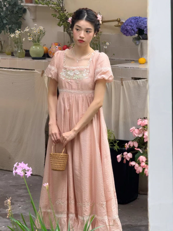 Side view of a vintage-inspired pink puff sleeve dress and braided hair with flowers, capturing a whimsical princesscore lifestyle moment in a cottage-style garden.