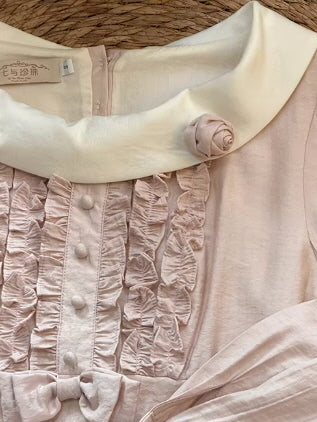 Close-up detail of vintage inspired blush pink dress with ruched ruffle bodice, decorative buttons and cream peter pan collar