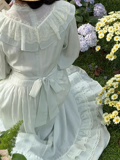 Back view of vintage cottagecore dress with waist ribbon tie and layered lace ruffle collar in soft sage green