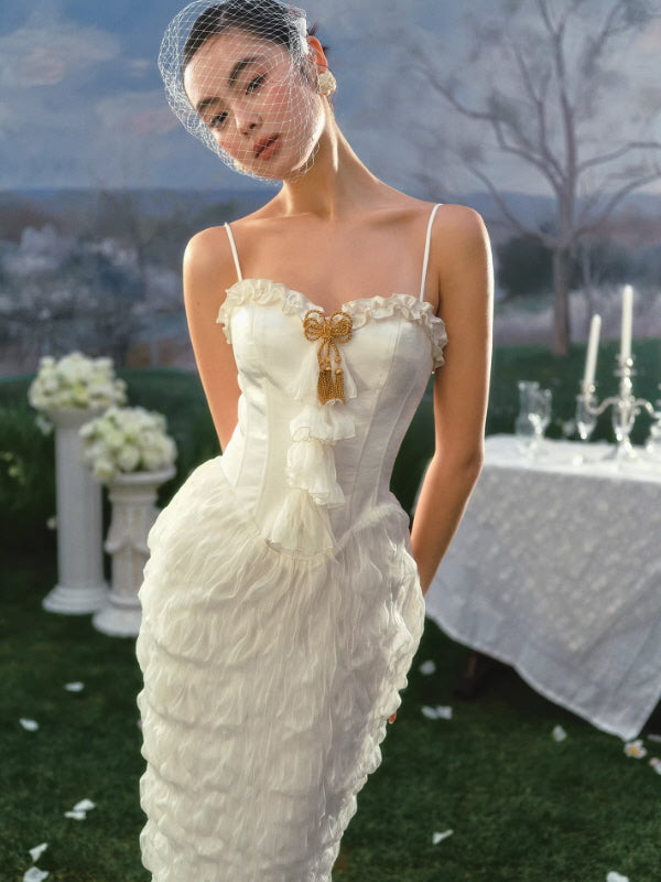 Vintage-inspired ivory corset dress with delicate straps and gold bow detail, feminine fitted silhouette