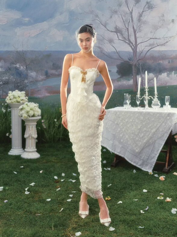 Full-length ivory lace dress with textured ruffles and slim silhouette, styled in dreamy outdoor garden scene