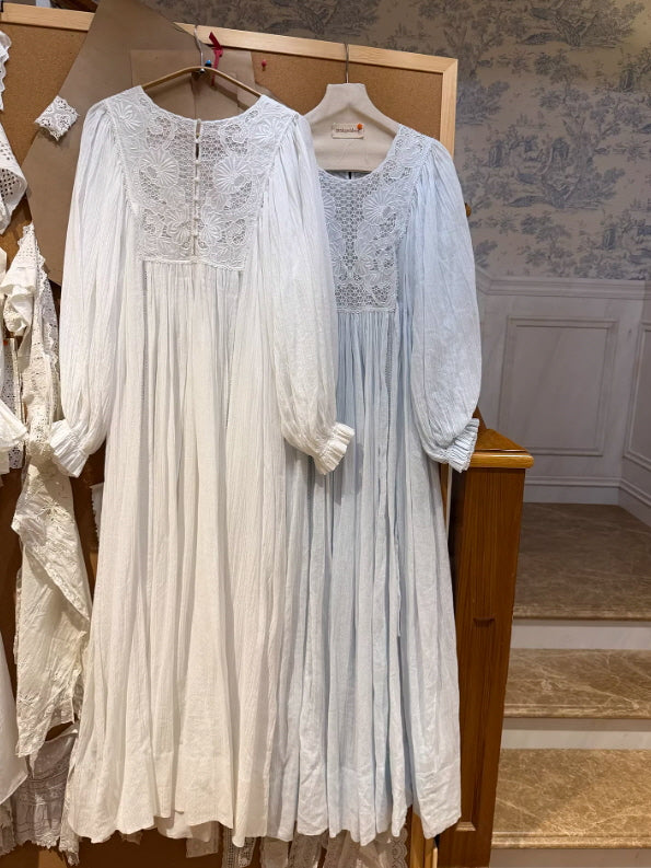 Two vintage inspired nightgowns in white and pale blue hanging on rack, soft pleated fabric and lace bodice detail