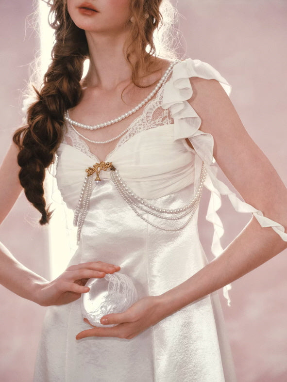 Ivory satin fairycore dress with pearl draped chains, lace neckline, and soft ruffle straps, vintage princess aesthetic close-up